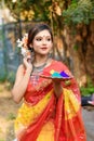 Portrait of pretty young indian girl wearing traditional saree and jewellery, holding powder colours in plate Royalty Free Stock Photo