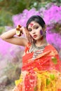 Portrait of pretty young indian girl wearing traditional saree and jewellery, playing with colors on the festival of colours Royalty Free Stock Photo