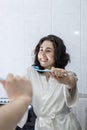 portrait of a pretty young latin girl holding a toothbrush and smiling in front of the mirror. Royalty Free Stock Photo