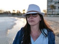 Portrait of a pretty young woman on the beach in a white hat and sunglasses Royalty Free Stock Photo