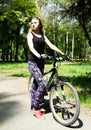 Portrait of pretty young woman with bicycle in a park - outdoor Royalty Free Stock Photo