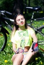 Portrait of pretty young woman with bicycle in a park - outdoor. girl sitting on the grass and drinks water from a Royalty Free Stock Photo