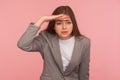 Portrait of pretty young woman in business suit holding hand over eyes and looking far away with attentive view Royalty Free Stock Photo