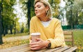 Portrait of pretty young woman drinking coffee at terrace cafetaria in the park. Female in the city street drinking hot cappuccino