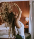 Portrait of pretty young woman flinging long brown hair into air in room by the window