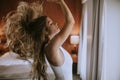 Portrait of pretty young woman flinging long brown hair into air in room by the window