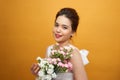 Portrait of a pretty young woman holding bouquet of carnation isolated over yellow background Royalty Free Stock Photo