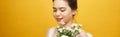 Portrait of a pretty young woman holding bouquet of carnation isolated over yellow background