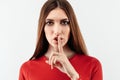 Portrait of a pretty young woman holding index finger on lips. Silence and secret concept. Studio shot, white background Royalty Free Stock Photo