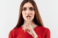 Portrait of a pretty young woman holding index finger on lips. Silence and secret concept. Studio shot, white background Royalty Free Stock Photo