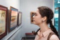 Portrait of a pretty young woman looking at a painting. An exhibition in an art gallery. Excursion and visit to the