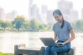 Portrait of pretty young woman sitting on bench  in park during summer day while using laptop of online shopping Royalty Free Stock Photo