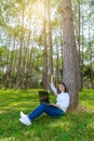 Portrait of pretty young woman sitting on green grass in park summer day while using laptop Royalty Free Stock Photo