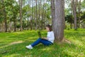 Portrait of pretty young woman sitting on green grass in park summer day while using laptop Royalty Free Stock Photo