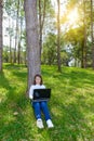 Portrait of pretty young woman sitting on green grass in park summer day while using laptop Royalty Free Stock Photo