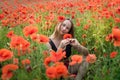 Portrait of a pretty young woman in sportswear sitting in blooming poppies field Royalty Free Stock Photo