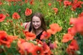 Portrait of a pretty young woman in sportswear sitting in blooming poppies field Royalty Free Stock Photo