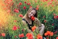 Portrait of a pretty young woman in sportswear sitting in blooming poppies field Royalty Free Stock Photo