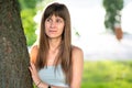 Portrait of pretty young woman standing neat tree trunk in summer