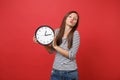 Portrait of pretty young woman in striped clothes blowing kisses, send air kiss, holding round clock isolated on bright Royalty Free Stock Photo