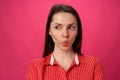 Portrait of pretty young woman sucked in her cheeks against pink background