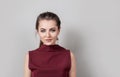 Portrait of pretty young woman wearing business clothes looking at camera with smile, standing against grey wall Royalty Free Stock Photo