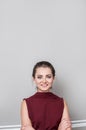 Portrait of pretty young woman wearing business clothes looking at camera with smile, standing against grey wall Royalty Free Stock Photo