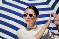 Portrait of a pretty young woman in white lace dress, white pearl necklace and light pink sunglasses Royalty Free Stock Photo