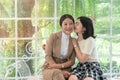 Portrait of pretty woman kissing on the cheek and embracing her mother while there is sitting on white sofa in living room Royalty Free Stock Photo