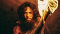 Portrait of Primeval Caveman Wearing Animal Skin Standing in His Cave At Night, Holding Torch with