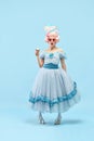 Portrait with princess, queen wearing elegant dress holding ice cream with surprised face over blue background. Concept