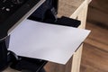 A portrait of a printer with an white empty piece of paper in its printed output tray. The blank page can be used to display some Royalty Free Stock Photo