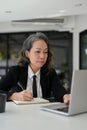 Professional Asian aged businesswoman focusing on her task, using laptop, working in the office Royalty Free Stock Photo