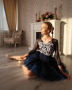 Portrait of a professional ballet dancer sitting on the wooden floor. Ballet concept.