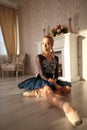 Portrait of a professional ballet dancer sitting on the wooden floor. Female ballerina having a rest. Ballet concept. Royalty Free Stock Photo