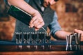 Portrait of professional barman pouring alcoholic in shot glasses at bar