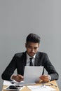 Portrait of a professional businessman looking at his documents while sitting on office desk on grey background. Royalty Free Stock Photo