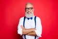 Portrait of professional, cool, old man with beaming smile having his arms crossed, looking at camera, wearing blue bow-tie and s Royalty Free Stock Photo