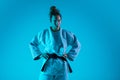 Portrait of professional female judoist isolated on blue studio background in neon light. Healthy lifestyle, sport Royalty Free Stock Photo