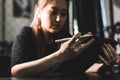 Portrait of a professional female tattooist in a tattoo studio draws a sketch on a tablet