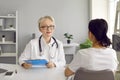 Portrait of professional friendly senior female doctor conducting consultation for patient.