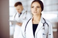 Portrait of a professional friendly woman doctor with a stethoscope, standing with a colleague in a clinic. Young