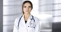 Portrait of a professional friendly woman doctor with a stethoscope, standing straight in a clinic. Physician at work in