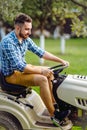 professional lawn mower with worker cutting the grass in a garden Royalty Free Stock Photo