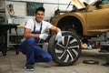 Portrait of professional mechanic with car wheel at automobile repair shop Royalty Free Stock Photo