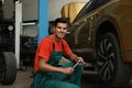Portrait of professional mechanic with tire wrench near car at automobile repair shop Royalty Free Stock Photo