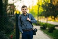 Portrait of professional photographer outside. Man use best camera and leather strap. Handsome confident young man in