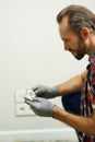 Portrait of professional repairman, electrician wearing protective gloves while installing wall plug socket in a new Royalty Free Stock Photo