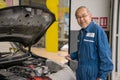 Portrait of professional senior car mechanic standing near  automobile working in the garage workshop Royalty Free Stock Photo