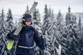 Male skier in goggles with professional ski equipment on his shoulders standing on slope top before skiing in mountains. Royalty Free Stock Photo